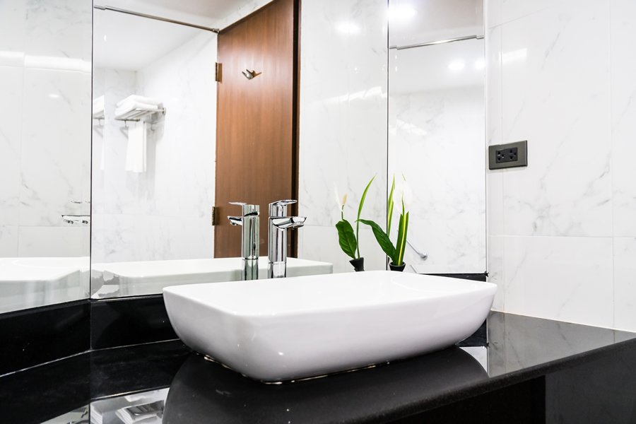 Modern bathroom remodeling in Warren NJ featuring a white ceramic vessel sink, black granite countertop, chrome faucets, and large mirrors.